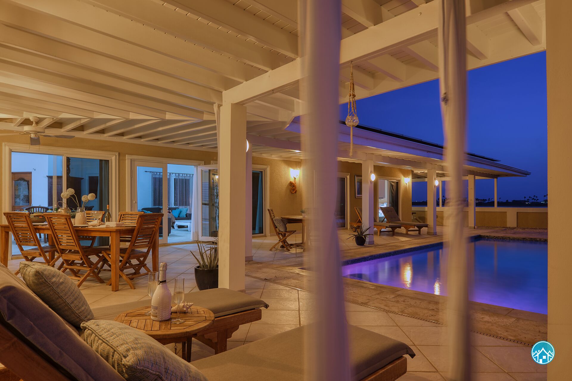 Amplio espacio interior con piscina, zona de comedor con mobiliario de madera y vistas al exterior.
