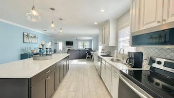 Una cocina moderna con una isla grande, armarios blancos y electrodomésticos de acero inoxidable.
