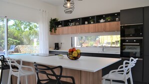 A modern kitchen with a central island, white bar stools, and a black and white color scheme.