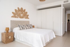 A bedroom with a bed, a nightstand, a wall art piece, and a wardrobe.