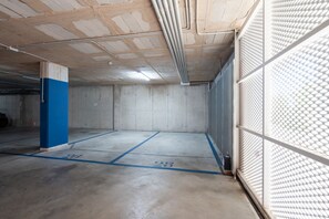 A parking garage with concrete walls, a blue pillar, and marked parking spaces.