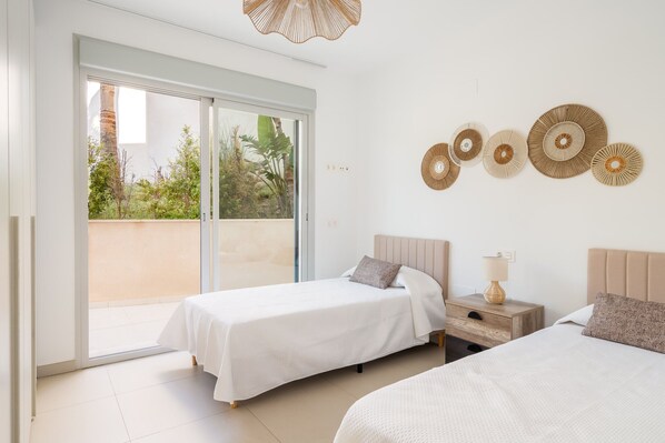 A bedroom with two beds, a nightstand, a lamp, and decorative wall art.