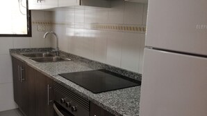 Une cuisine équipée d’un évier, d’une cuisinière, d’un four et d’un réfrigérateur.