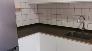 Keittiössä on valkoiset kaapit, ruostumattomasta teräksestä valmistettu pesuallas ja musta työtaso.