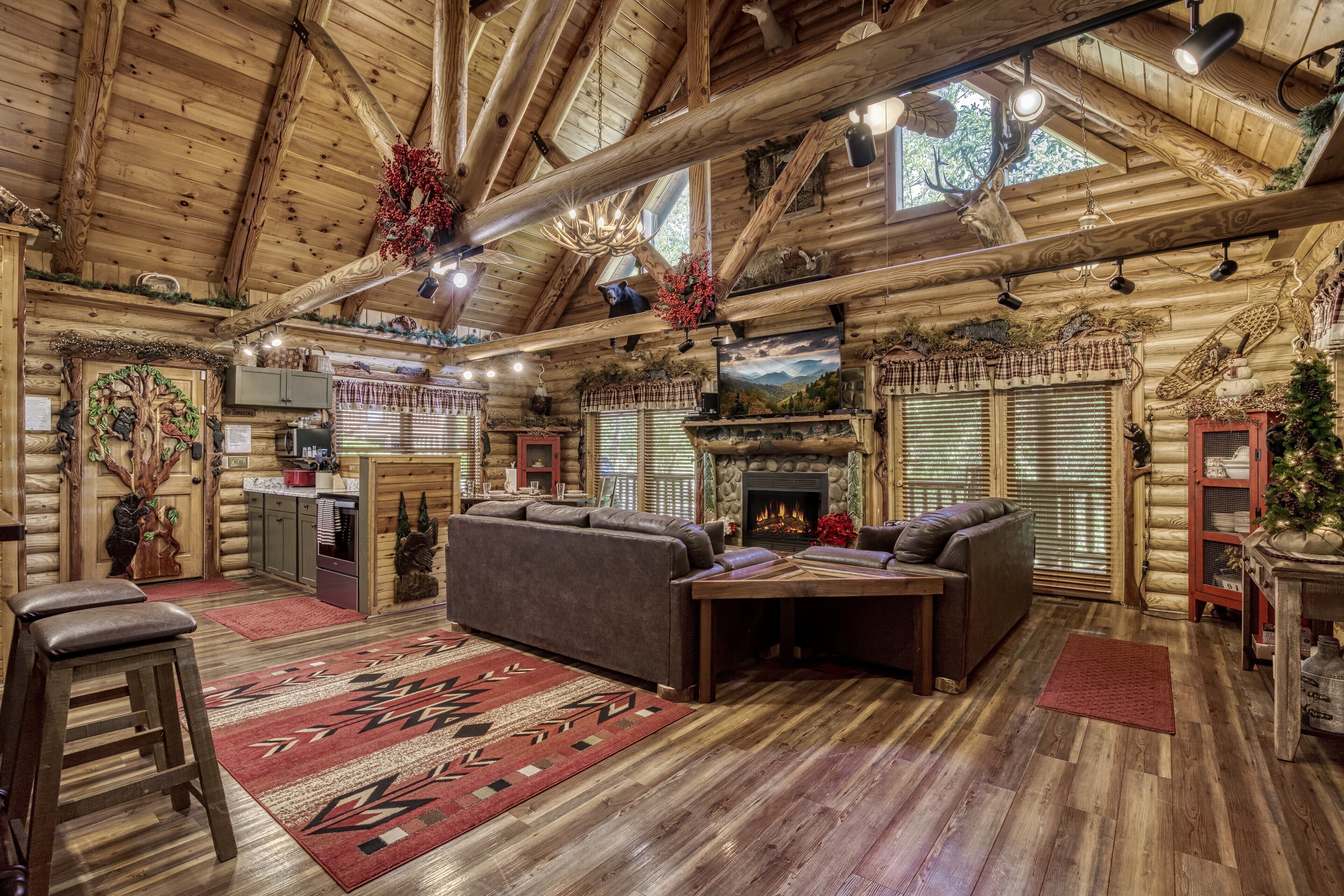 A log cabin interior with a fireplace, wooden ceiling beams, and a cozy seating area.