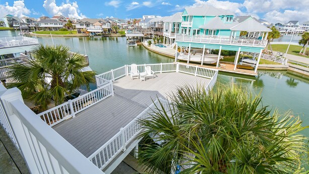 A waterfront property with a large deck, a pool, and a view of the water.