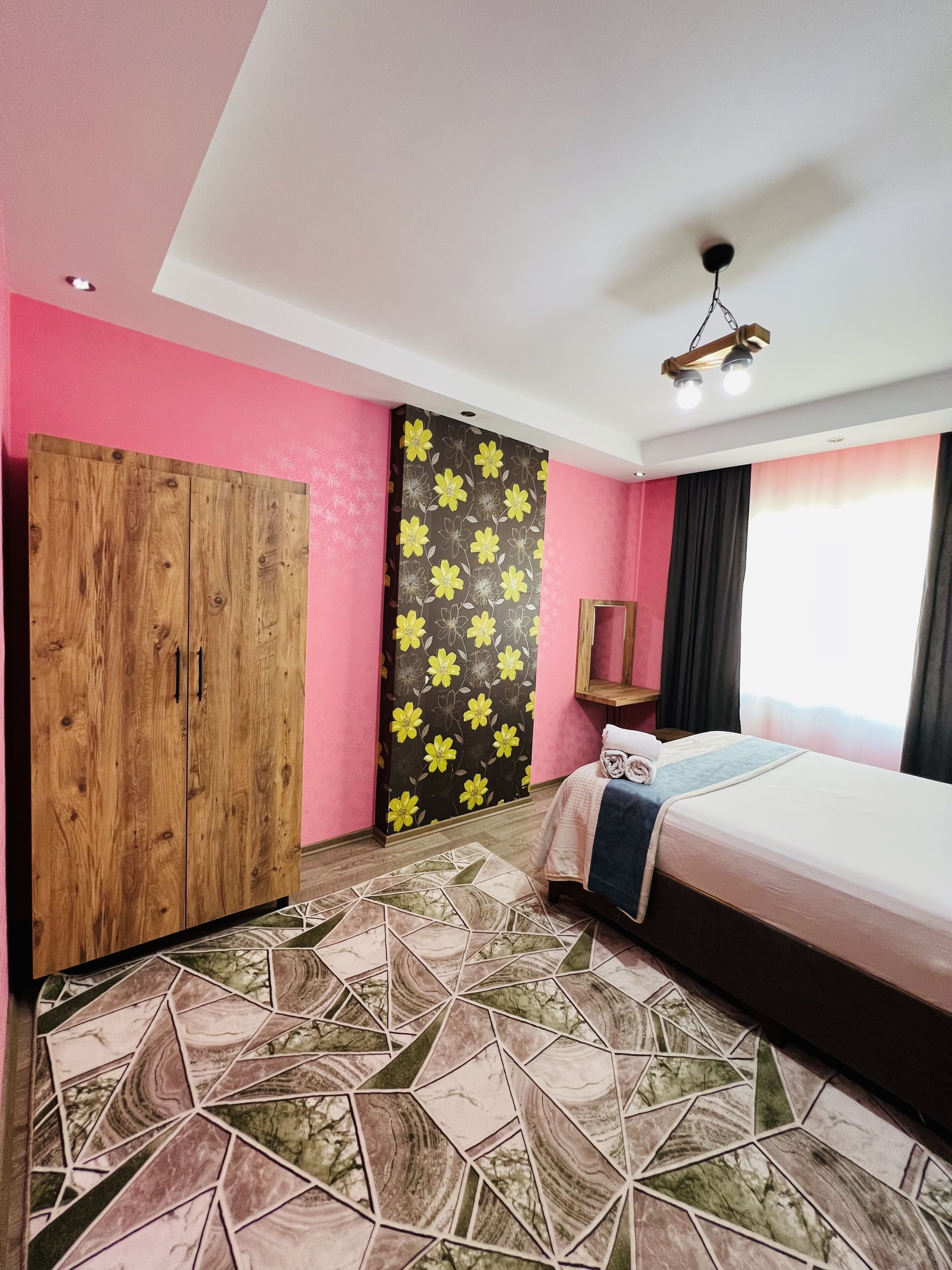 Un dormitorio con cama, armario, pared con estampado floral y suelo de diseño geométrico.