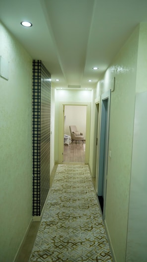 A hallway with patterned flooring, a chair, and doors leading to other rooms. - Aria Plus Ev Otel (Mersin)