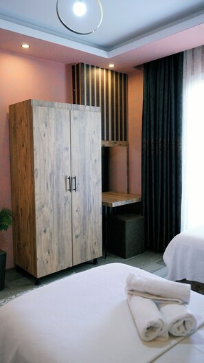 Habitación de hotel con un armario grande, una cama con toallas ordenadas y una ventana con cortinas oscuras.