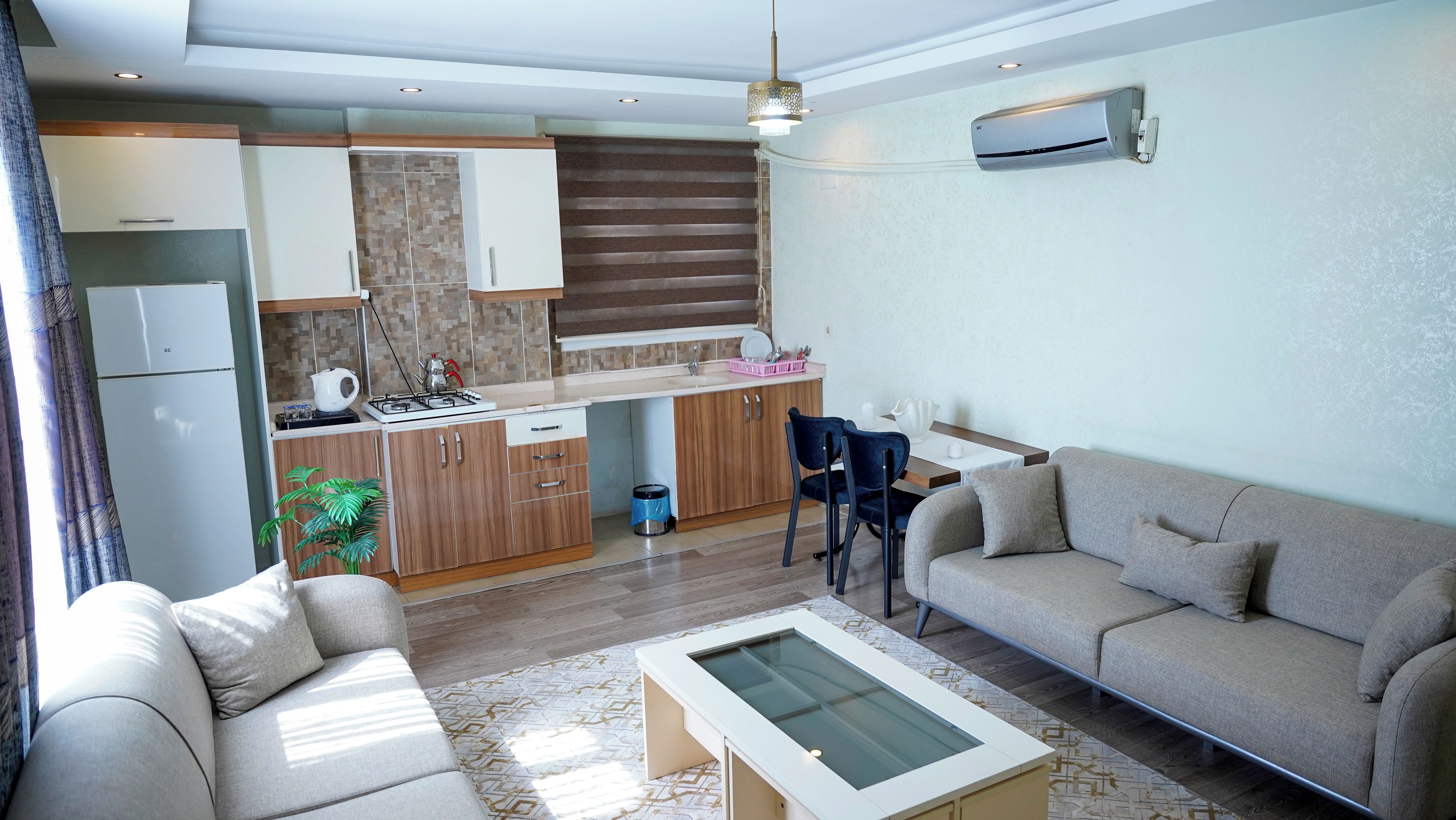 A modern living room with a sofa, a coffee table, and a dining area with chairs.