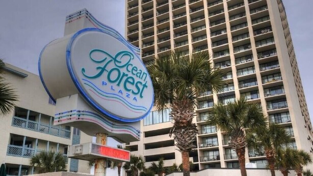 Une enseigne d’hôtel portant le nom « Ocean Forest Plaza » et, en arrière-plan, un grand immeuble.