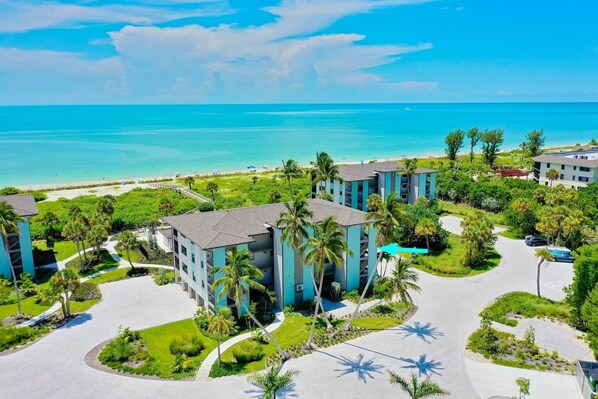 A resort with multiple buildings, a beach, and palm trees.