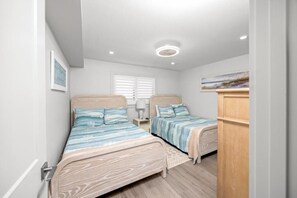 Une chambre avec deux lits, une table de chevet, une lampe et un tableau au mur.