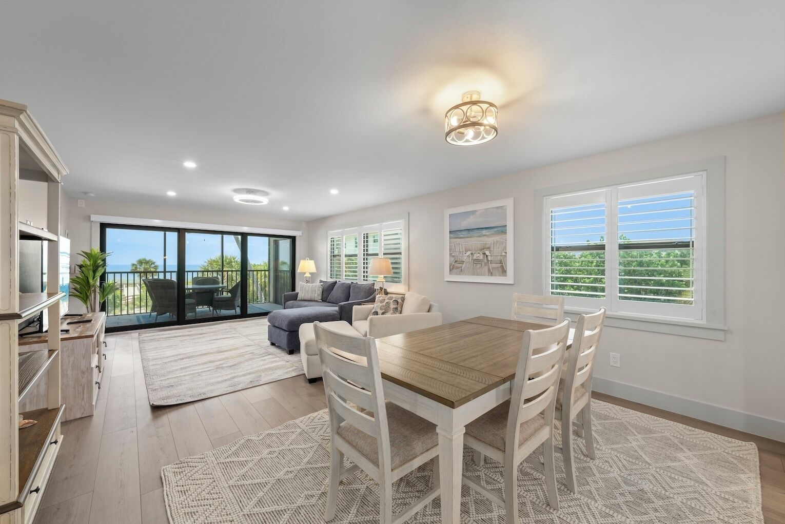 A spacious living area with a dining table, sofas, and a view of the outdoors.