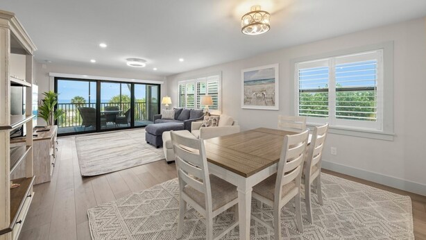 A spacious living area with a dining table, sofas, and a view of the outdoors. - Tarpon Beach 206: Beautiful Condo & Stunning Gulf Views to Match (Sanibel)