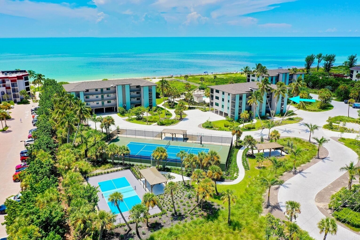 Un resort con piscina, canchas de tenis y vista al océano.