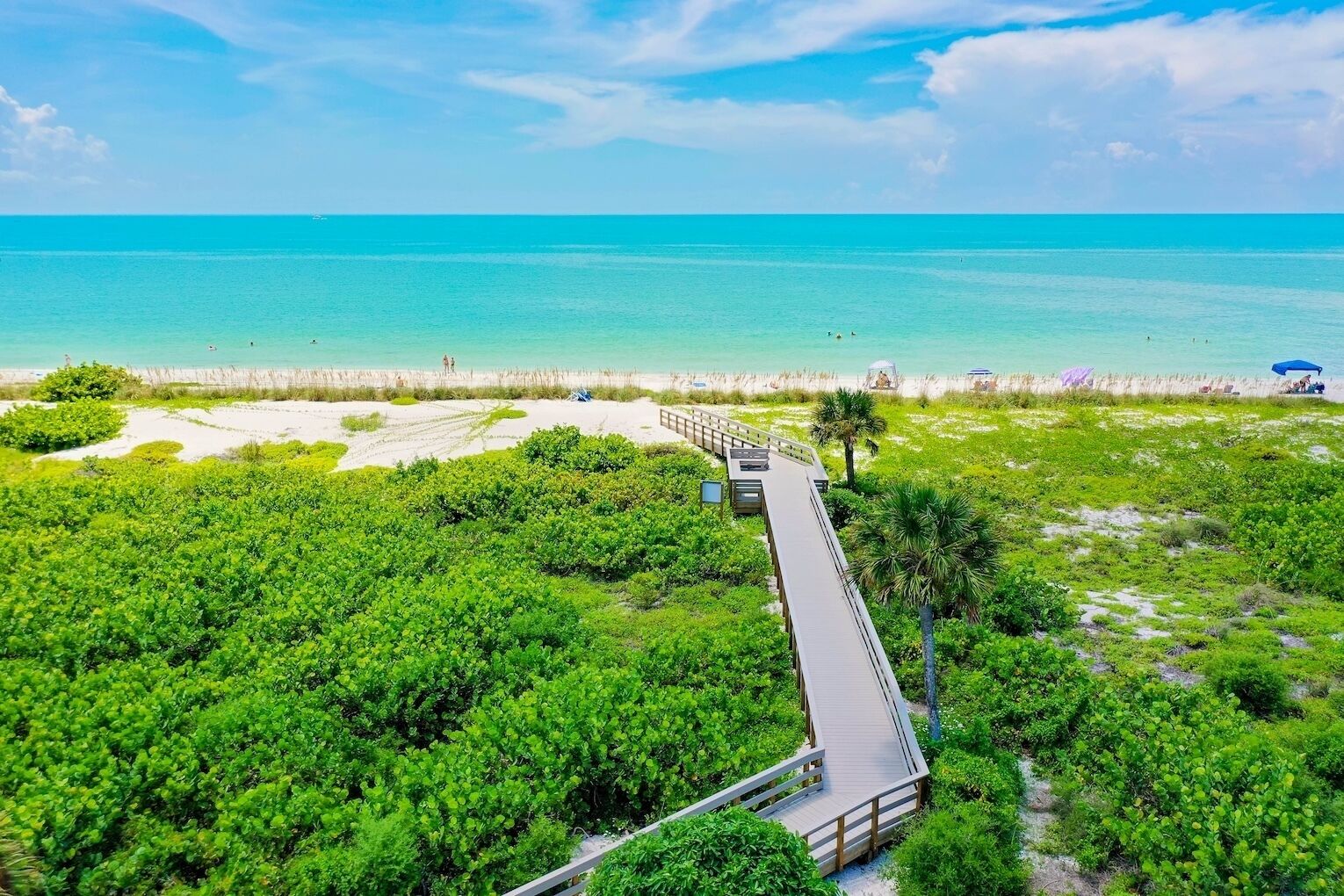 A coastal area with a wooden boardwalk leading to a beach.