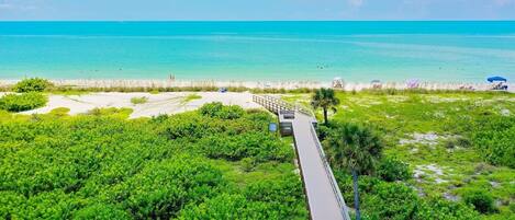Zona costera con un paseo marítimo de madera que conduce a una playa.