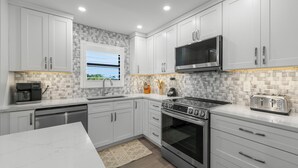 A modern kitchen with white cabinets, a stainless steel microwave, a toaster, and an LG oven. - Tarpon Beach 206: Beautiful Condo & Stunning Gulf Views to Match (Sanibel)