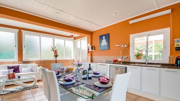 A modern kitchen with white cabinets, a glass dining table, and a view of the outdoors. - Central Finca in Mallorca Finca Alegre with pool (Lloseta)