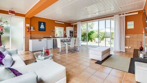 A spacious living area with a white sofa, a dining table, and a kitchen area with a refrigerator, oven, and sink. - Central Finca in Mallorca Finca Alegre with pool (Lloseta)