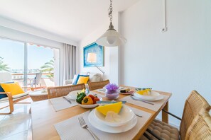 A dining area with a table set for two, a view of the sea, and a painting on the wall. - Apartment Maritimo in Puerto Alcudia seafront (Alcúdia)