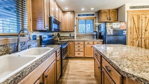 A kitchen with wooden cabinets, granite countertops, a double sink, a microwave, and a refrigerator. - Modern decor condo in Downtown WP w/access to Rec center w/pool, hot tub and (Winter Park)