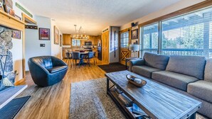 A modern living room with a sofa, coffee table, and a dining area with chairs and a table. - Modern decor condo in Downtown WP w/access to Rec center w/pool, hot tub and (Winter Park)