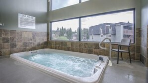 A spa room with a hot tub, a window with a view of buildings, and a sign detailing spa rules. - Modern decor condo in Downtown WP w/access to Rec center w/pool, hot tub and (Winter Park)