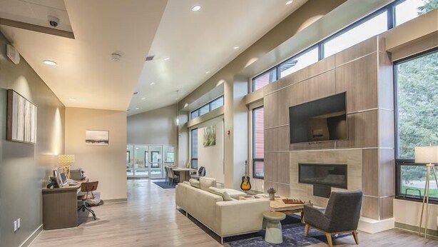 A modern living room with a fireplace, large windows, and a dining area. - Modern decor condo in Downtown WP w/access to Rec center w/pool, hot tub and (Winter Park)