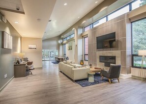 A modern living room with a fireplace, large windows, and a dining area. - Modern decor condo in Downtown WP w/access to Rec center w/pool, hot tub and (Winter Park)