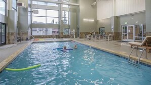 An indoor swimming pool with clear water, a lifeguard chair, and a poolside area with chairs and tables. - Modern decor condo in Downtown WP w/access to Rec center w/pool, hot tub and (Winter Park)
