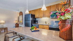 A kitchen with wooden cabinets, a stainless steel refrigerator, a built-in oven, and a granite countertop.