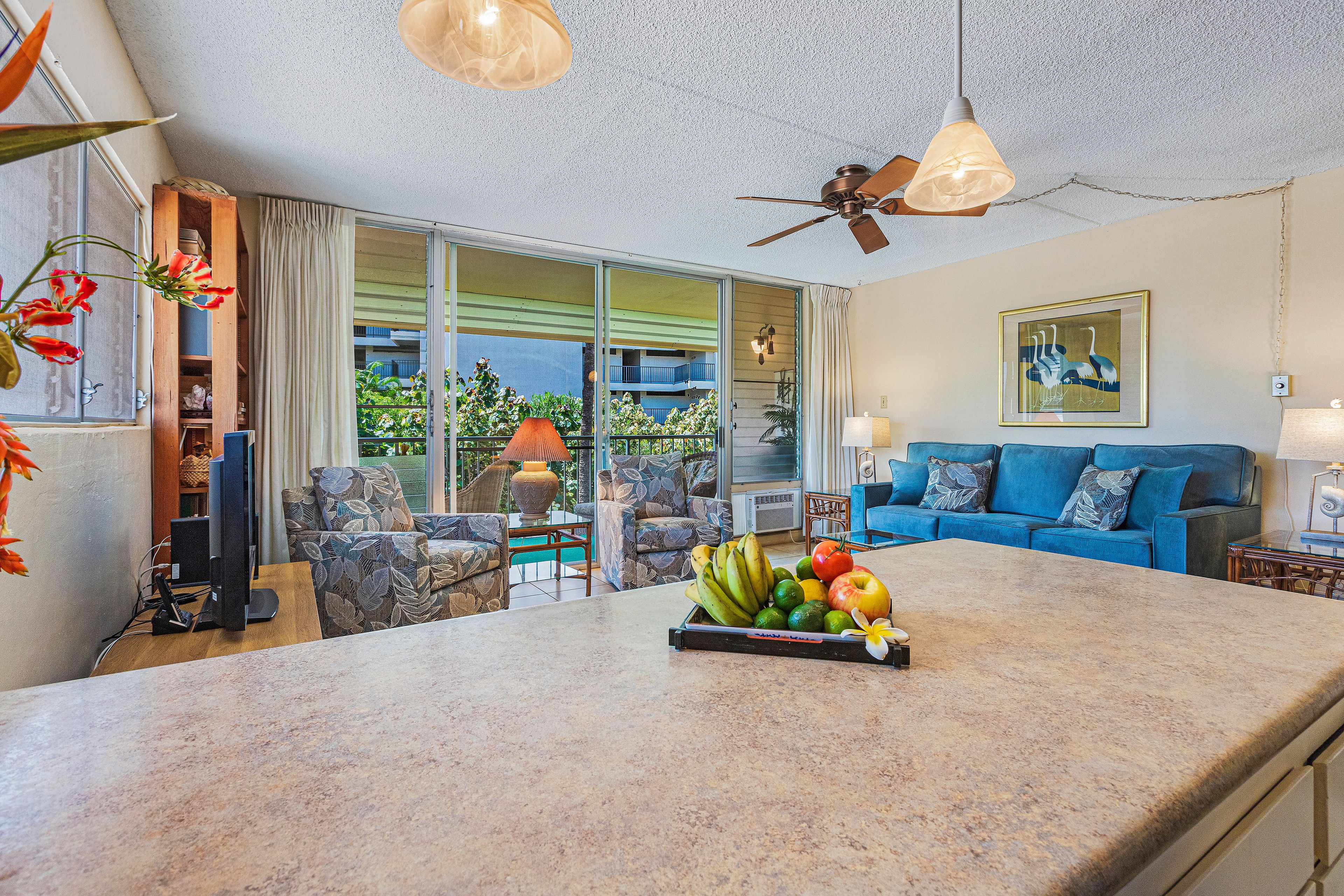 A spacious living area with a large island counter, a blue sofa, and a ceiling fan.