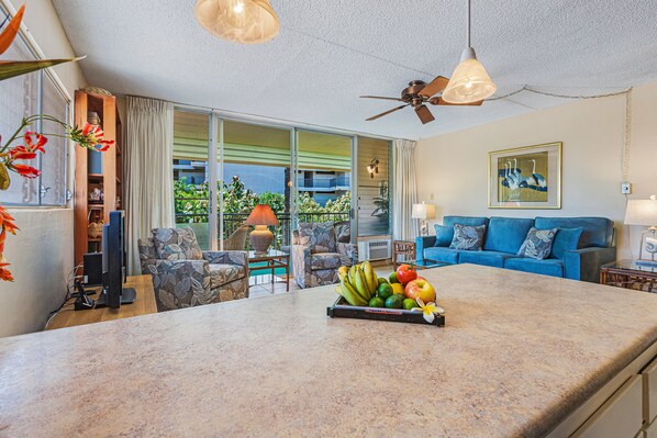 A spacious living area with a large island counter, a blue sofa, and a ceiling fan.