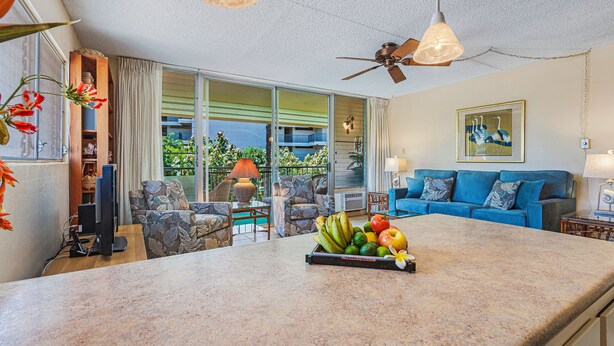 A spacious living area with a large island counter, a blue sofa, and a ceiling fan.