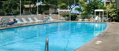 Una piscina con sillas de descanso y banderas estadounidenses.