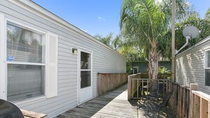A wooden deck with a grill, a tree, and a fenced area with chairs. - KINGFISH LODGE - PRIVATE MAINTAINED 3 BEDROOM 2 BATHROOM PRIVATE RENTAL (Buras)