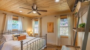 Ein Schlafzimmer mit Metallbettgestell, Holzboden und Deckenventilator.