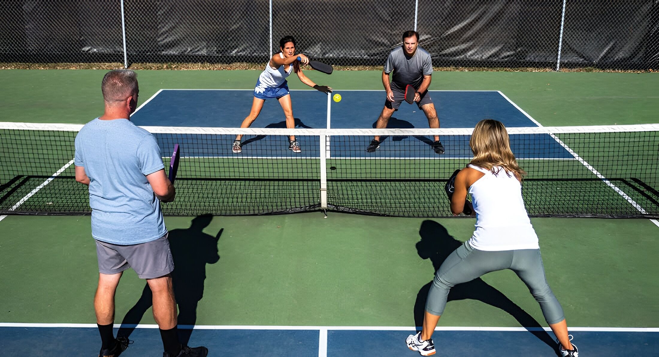 A tennis court with four players engaged in a match.