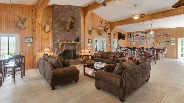 A spacious living room with a fireplace, wooden walls, and antler decorations.