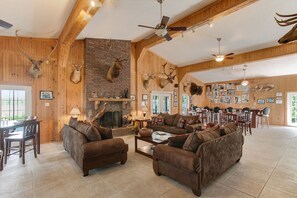 A spacious living room with a fireplace, wooden walls, and antler decorations. - EXCEPTIONAL EXCLUSIVE ONE-OF-A-KIND 5 BEDROOM 5 BATH LODGE IN VENICE (Boothville-Venice)