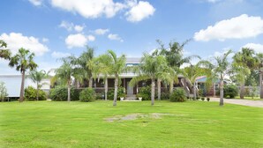 A house with a front yard, palm trees, and a clear sky.