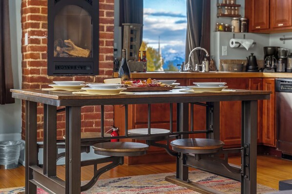 A rustic kitchen with a brick wall, wooden cabinets, and a large window with a view.