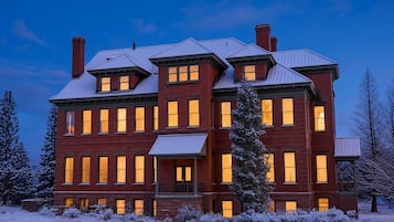 A large, multi-story brick building with multiple windows and a snow-covered landscape.