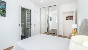 Ein modernes Schlafzimmer mit einem großen Bett, einem begehbaren Kleiderschrank und einem Badezimmer mit Handtuchhalter.