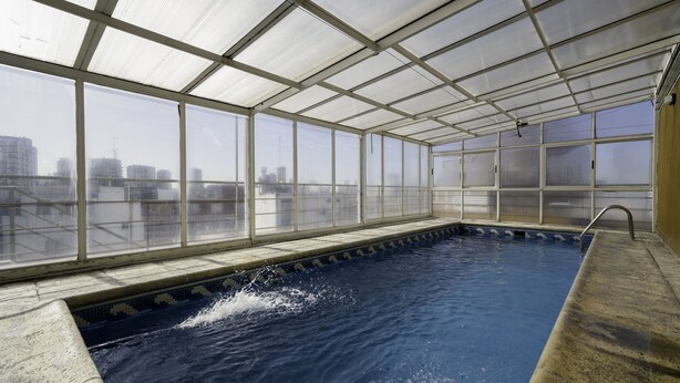 Une piscine intérieure avec vue sur la ville, grâce à de grandes fenêtres.