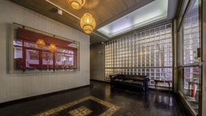 Un hall d’entrée spacieux, doté d’un tapis à motifs, d’un canapé en cuir noir et d’une grande fenêtre à carreaux.