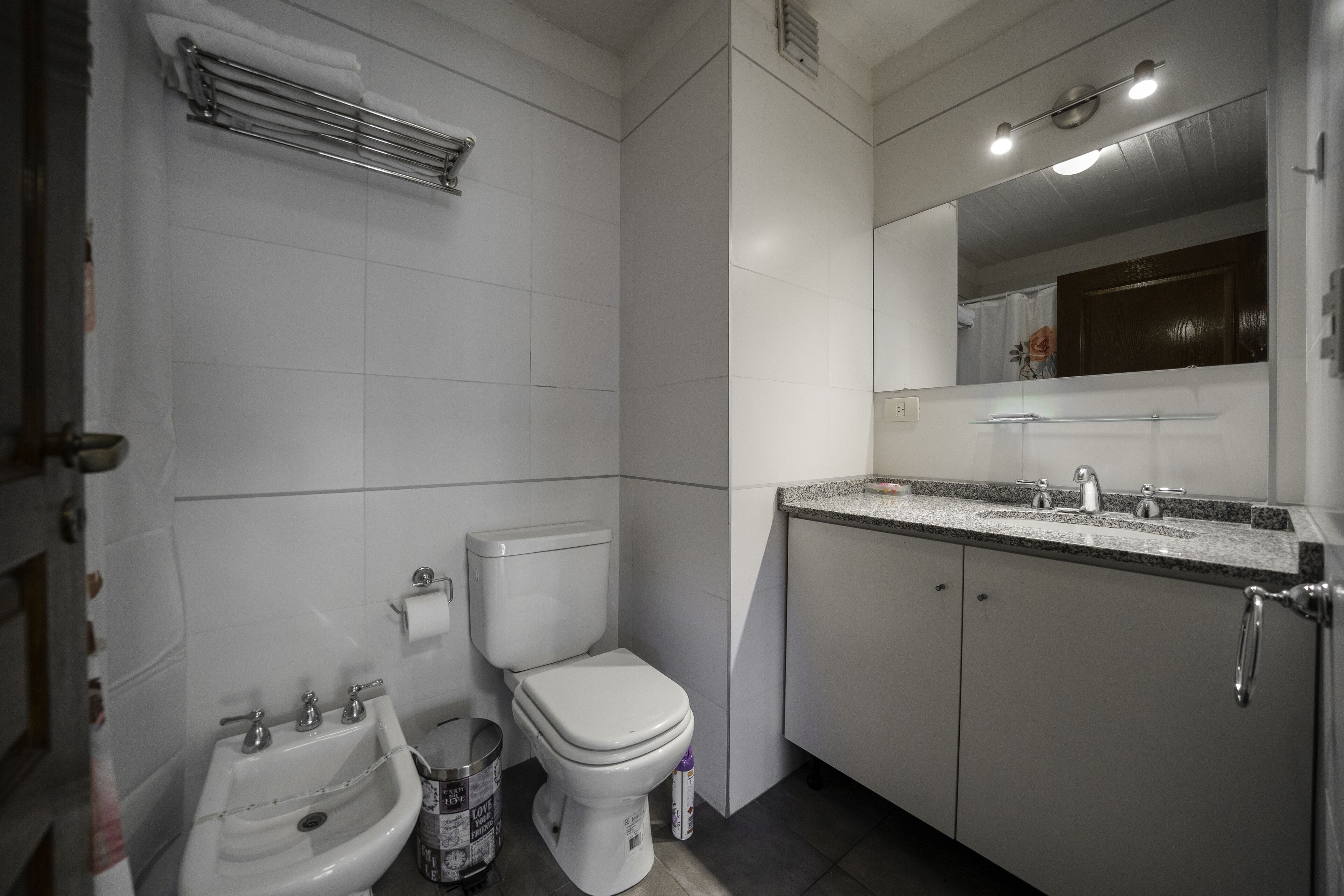 A bathroom with a toilet, bidet, sink, and mirror.