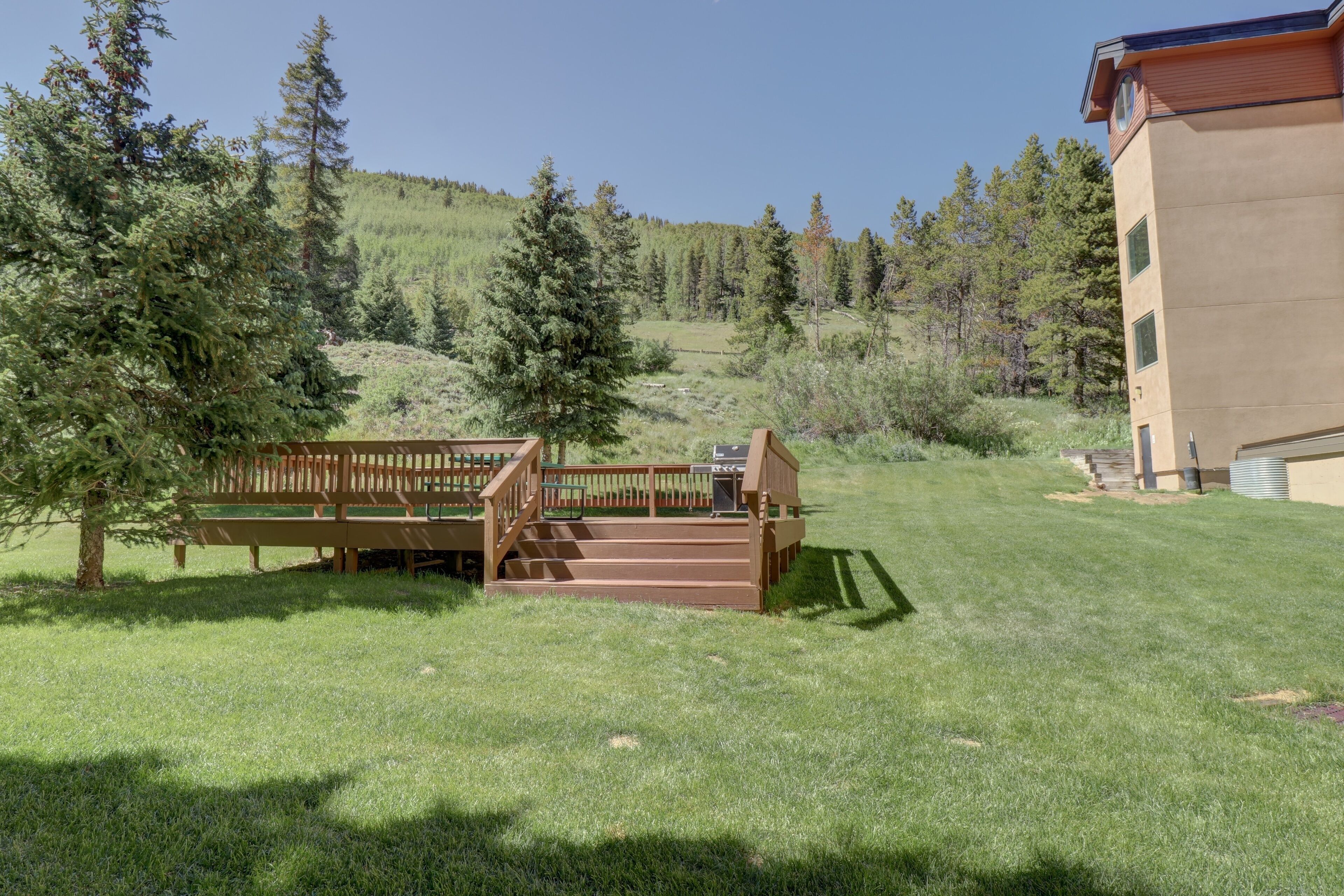 A wooden deck with a bench and steps leading to a building.